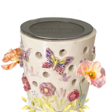 „Detailansicht: farbenfrohe handgemalte Blüten und Schmetterlinge auf dem Stövchen aus Keramik“